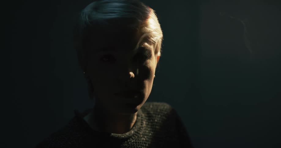 Close up of a female model smoking in a dimly lit room