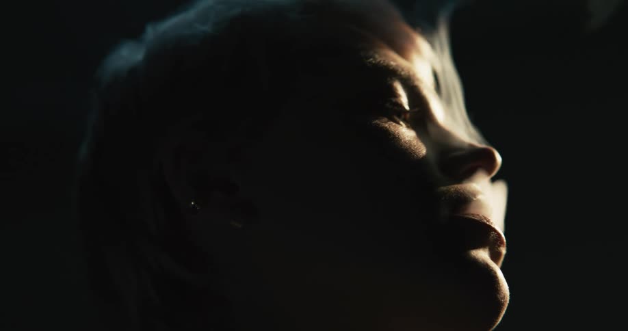 A woman is smoking a cigarette outdoors at night