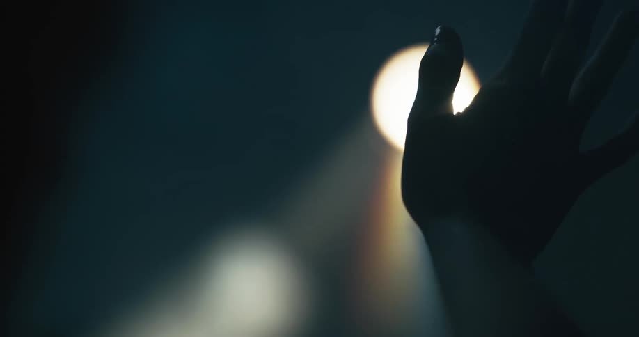 A close up of a hand waving in front of a light