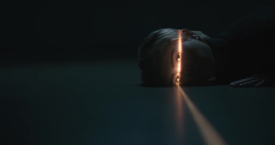 Young short haired blonde woman looking at the camera inside a dimly lit room