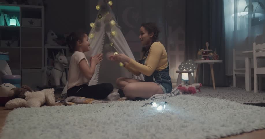Two girls playing together while sitting at the carpet inside one of the girls room