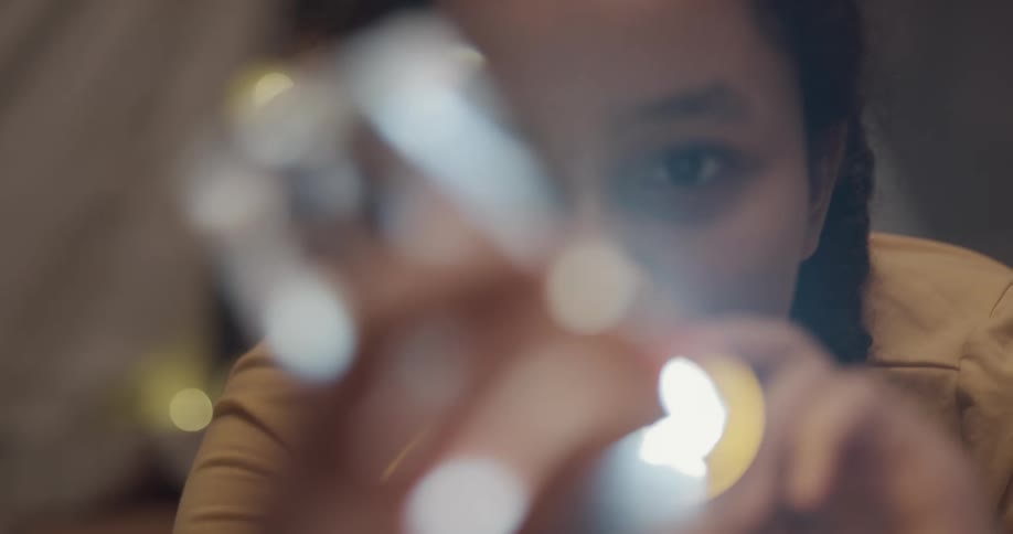 Young black woman examines a piece of crystal with a flashlight