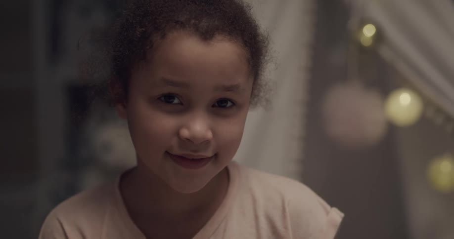 Young girl looking at the camera in a room at home
