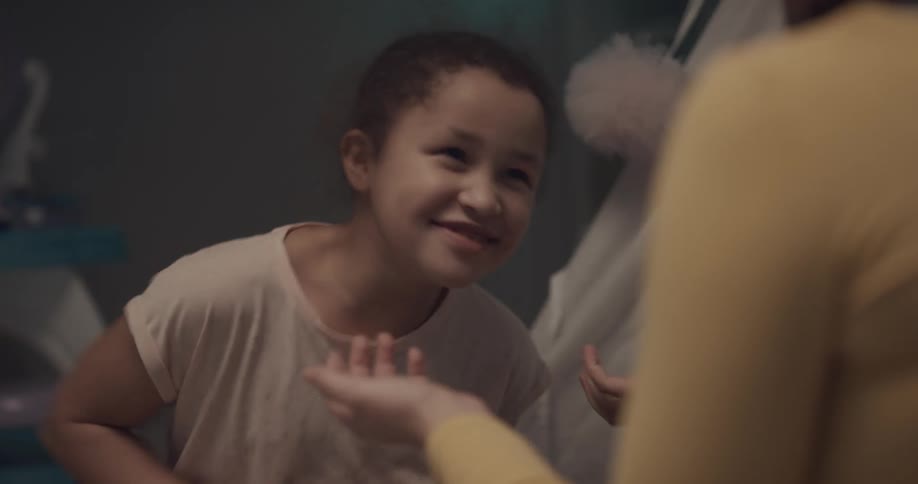 A girl plays red hands with her older sister indoors during the day
