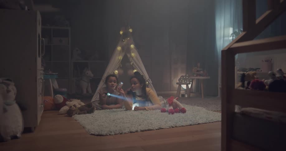 Two girls in a room on the floor with flashlights shining it through a crystal