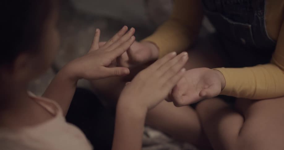 Two girls sitting and playing a game involving their hands
