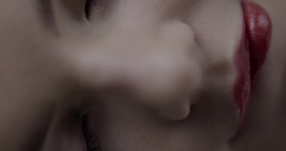 Birds eye view of a womans face as she wears bright red lipstick and chews on her lip