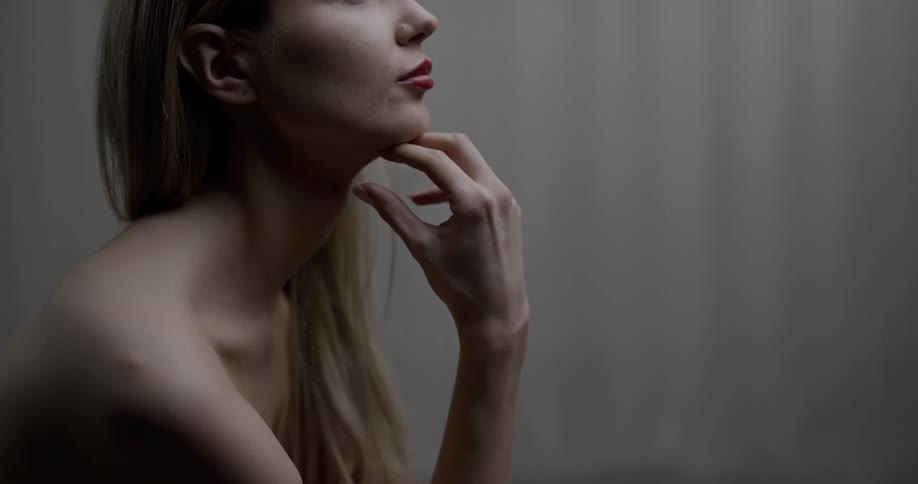 A shirtless woman posing with her hand under her chin