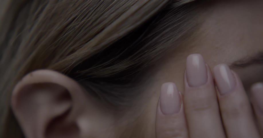 Close up of a woman rubbing the side of her face with her hands
