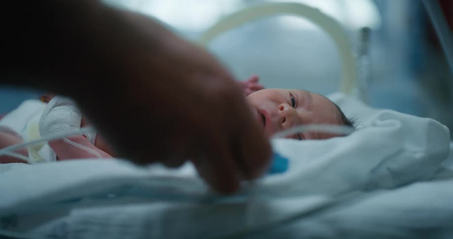 Newborn baby inside an incubator treated by medics in a hospital