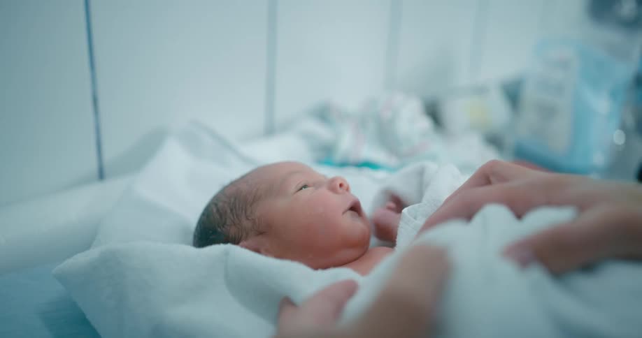 A baby is on a table being rocked with two hands