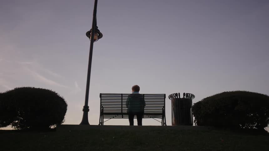 A person is sitting on a bench at sunset