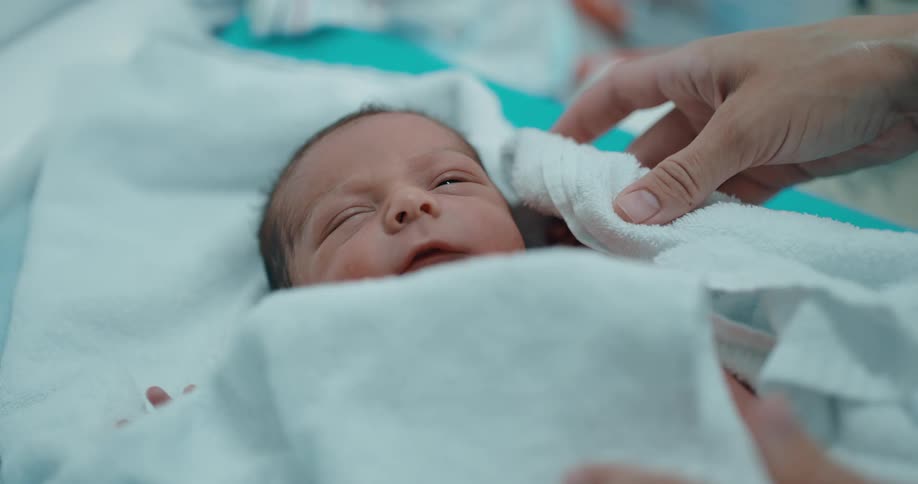 Nurse drying a newborn baby with a towel in the hospital
