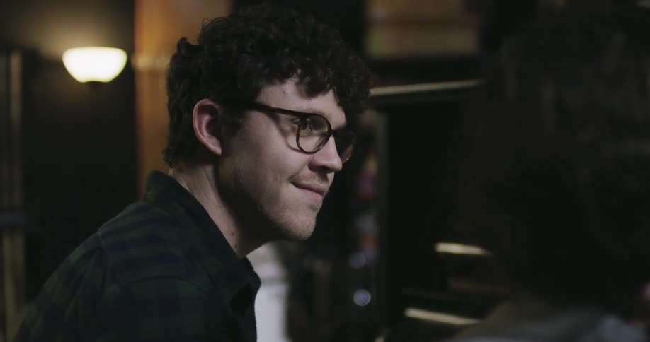 A man wearing glasses is sitting as he smiles