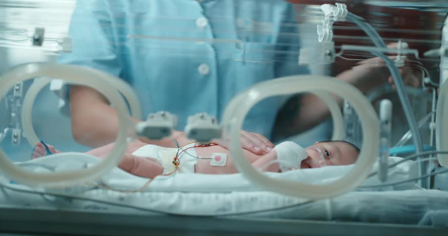 Woman touches baby lying in incubator in hospital