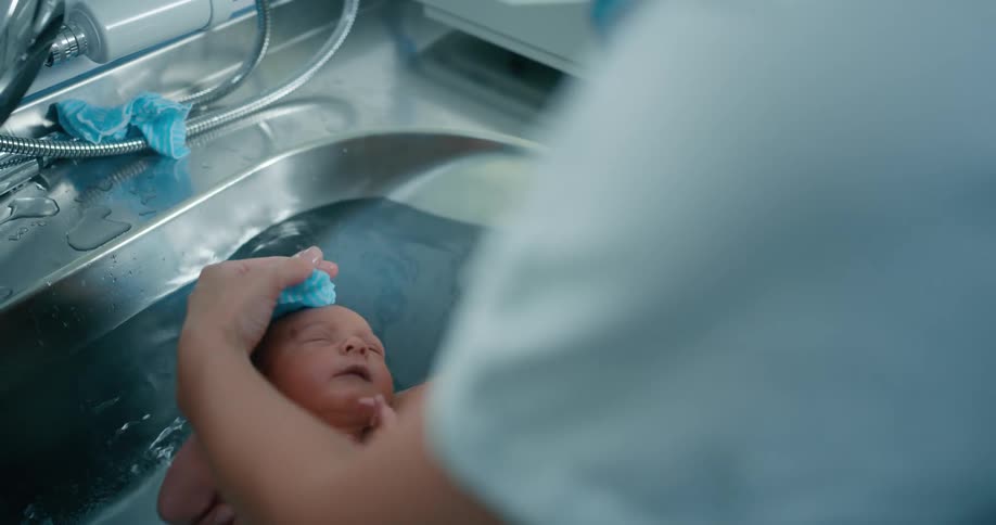 A nurse bathes a newborn baby