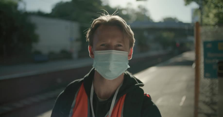 A man is standing by the road wearing a mask