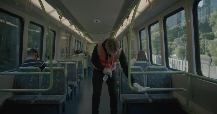 A worker cleaning down a bar in a public transit vehicle