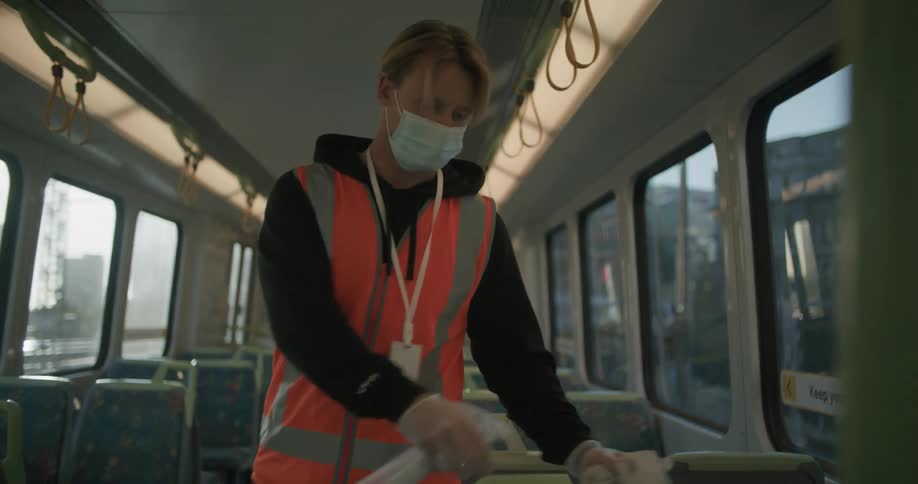 Man working by cleaning the interior of a bus with a towel