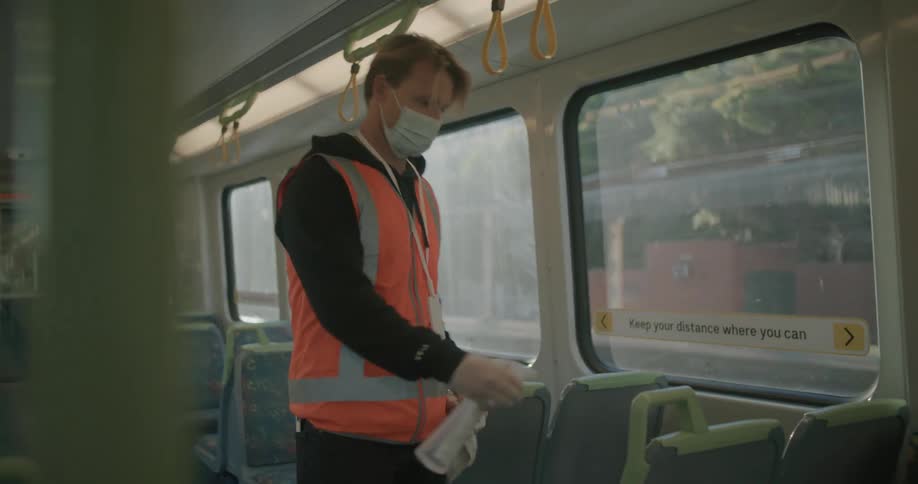 A man cleans handles on seats on a bus