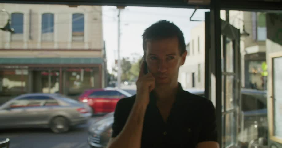 A man stands inside an empty store talking on a cell phone