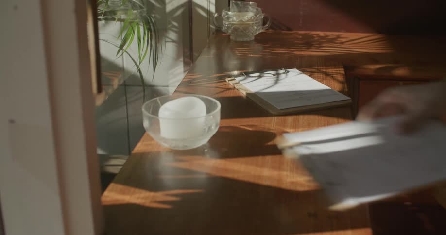 A person places two clipboards on the counter by the window