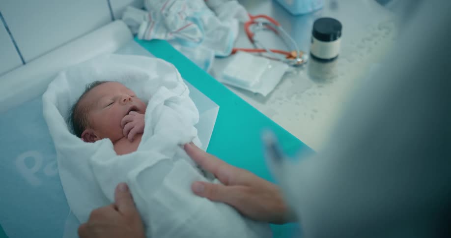 A newborn wrapped up in a blanket with a doctor