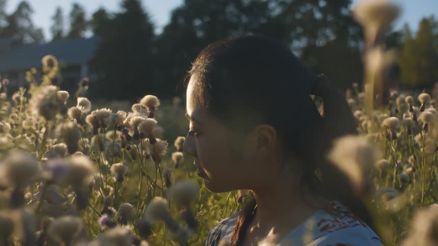 A woman is sitting in a field of flowers