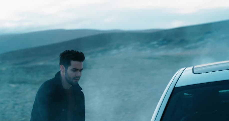 Man running through the smoke on a field boards a white car at evening