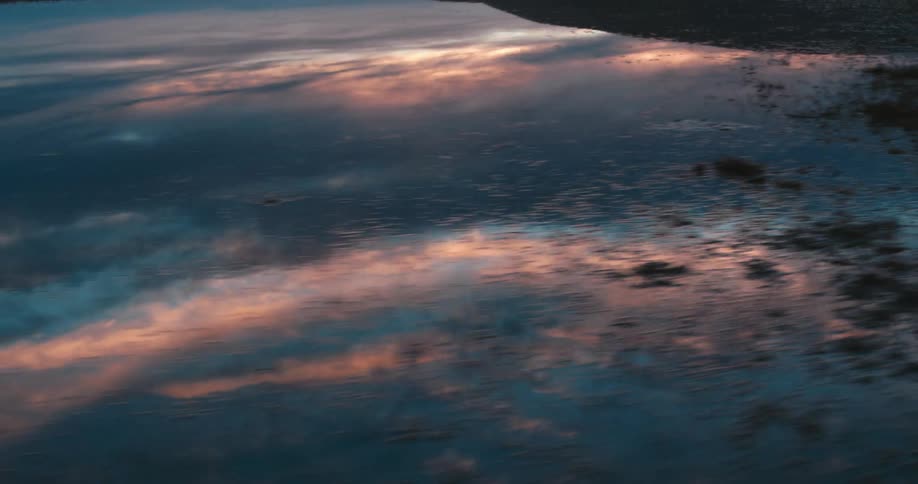 Clouds reflect on a small area of water at dusk