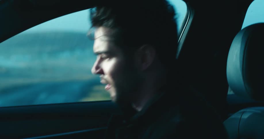 An anxious man hurriedly enters the drivers seat of a car