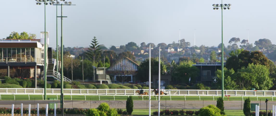 Two people racing on horses around a track