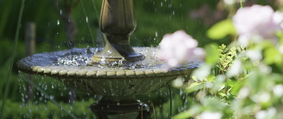 Slow motion footage of clear flowing water in a fountain on a garden