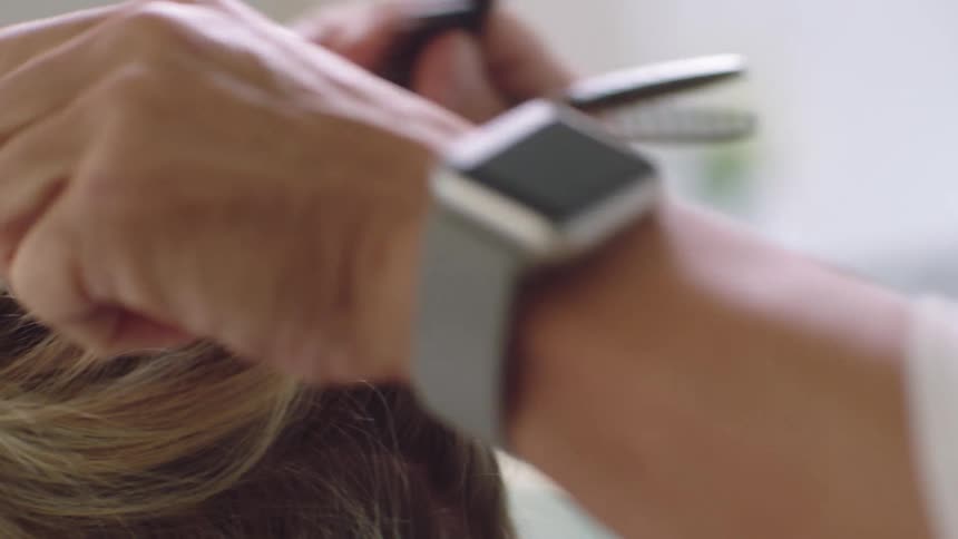 A hairstylist putting a clip into a clients hair