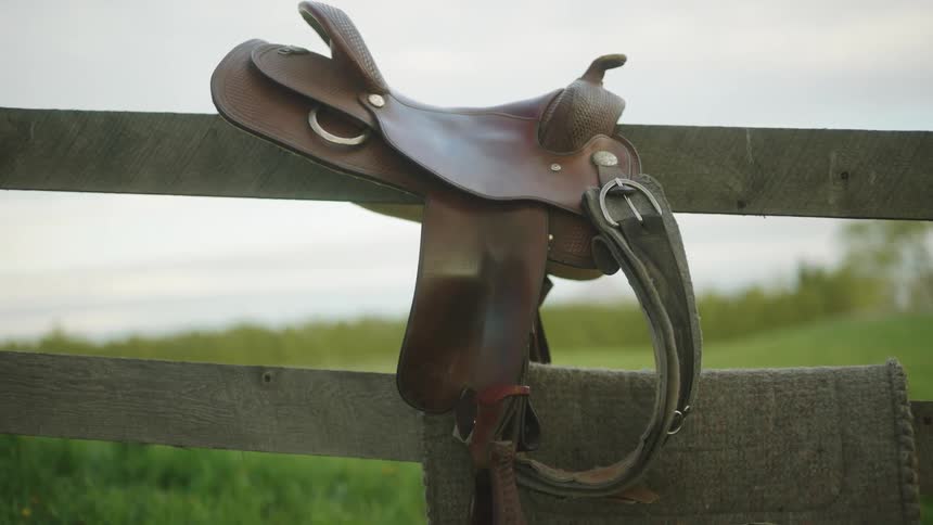 A saddle on a fence on a ranch