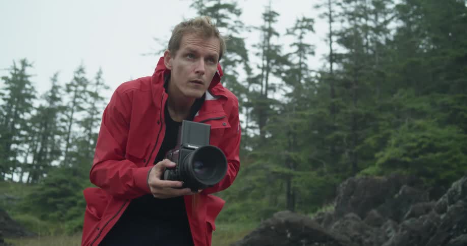 A man taking a photo with a medium format film camera near forest
