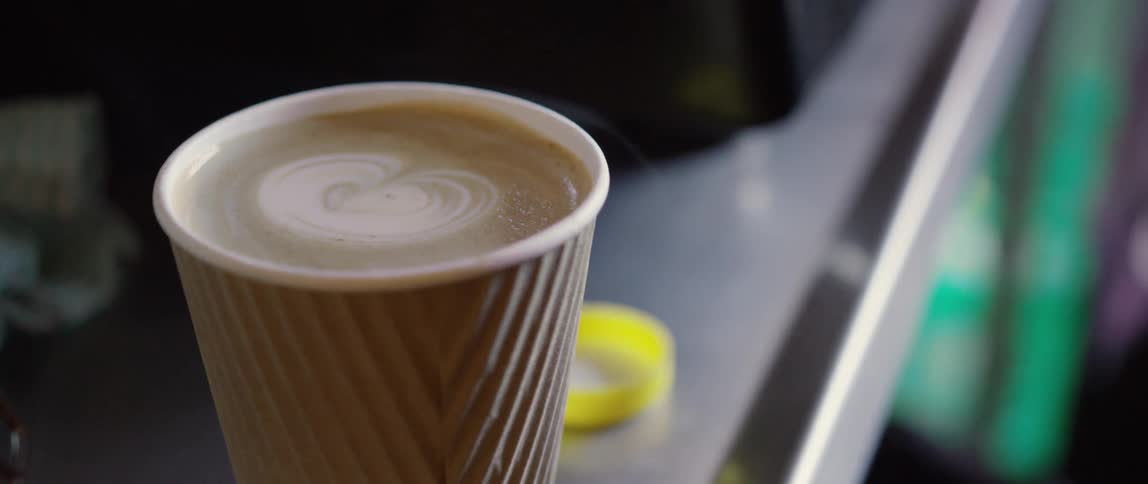 A white lid is placed on a paper coffee cup