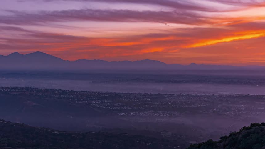A time lapse view of a landscape with a red sky and clouds moving across a skyline