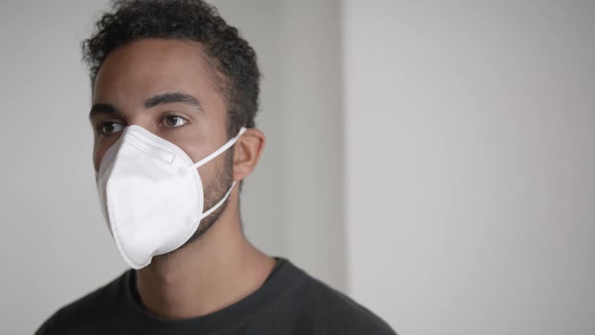 Young black man putting on a face mask then taking it off