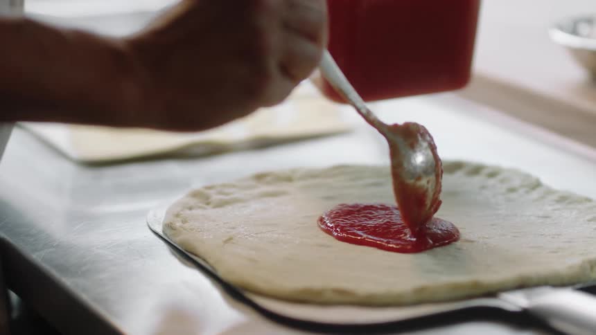 A person is cooking a pizza at a restaurant