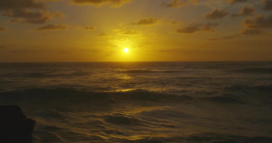 Beautiful sunset in an orange sky as ocean waves roll in
