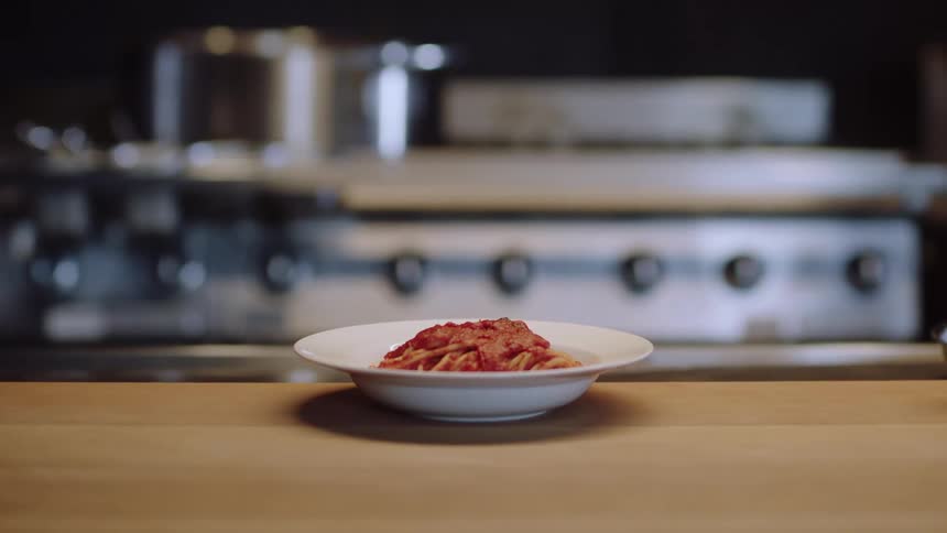 A plate of spaghetti sitting on a counter in a restaurant