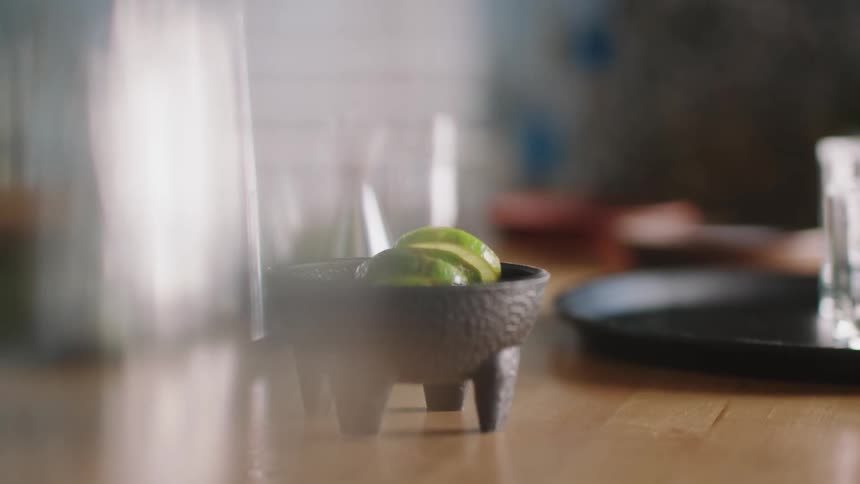 Lime slices in a bowl with legs on a table indoors