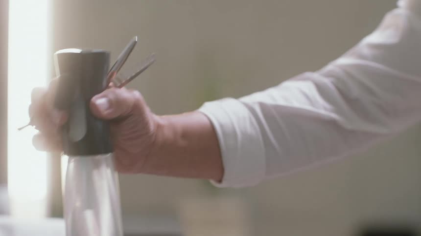 A person in a room with a tool picking up a bottle