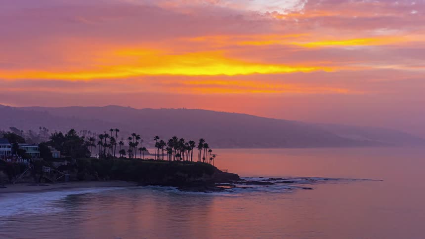 Time lapse of a red sky sunset over the mountains next to the ocean