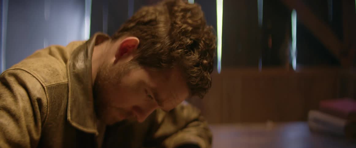 A man is writing on a piece of paper while sitting indoors