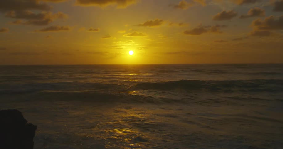 Landscape of sun setting against an ocean and clouds