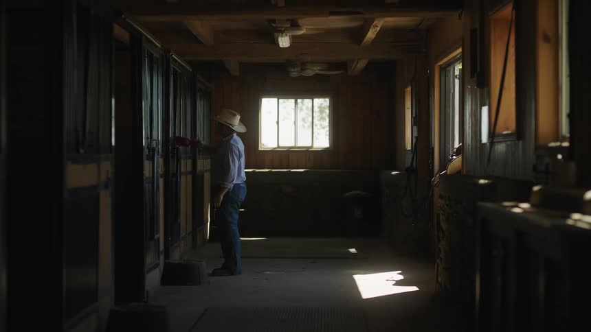 A man in a barn gets out a scoop of food