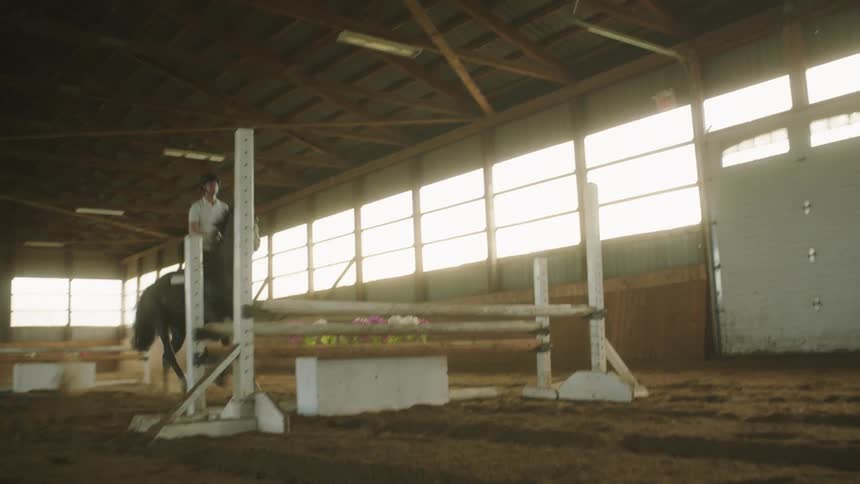 A man riding a horse on an indoors obstacle course
