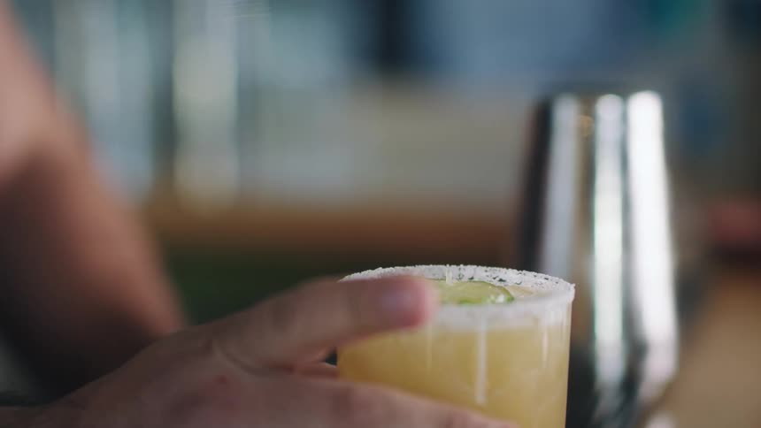 Bartender topping a cocktail with a lemon slice in a bar